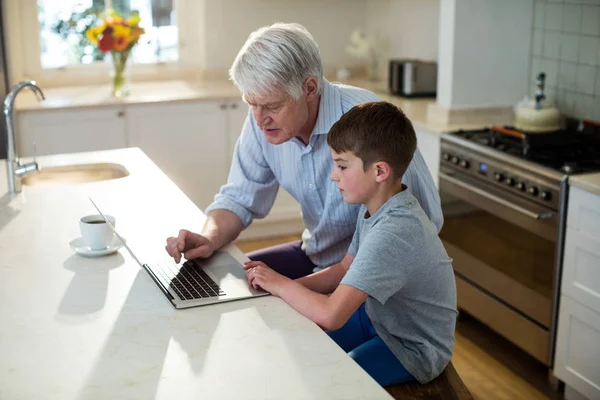 Grandson using laptop with grandfather — Stock Photo, Image