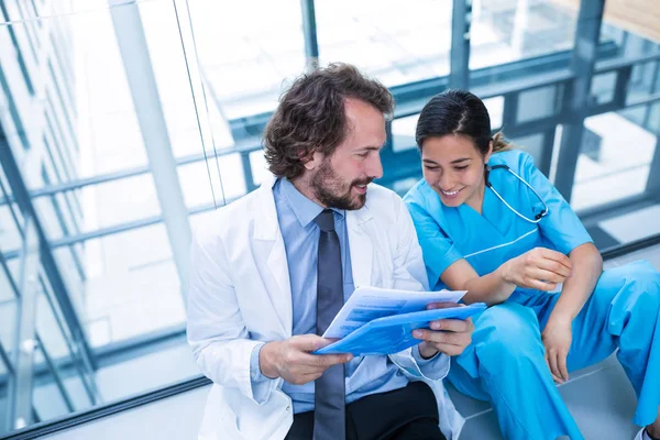 Glada läkare och sjuksköterska diskutera över en rapport — Stockfoto