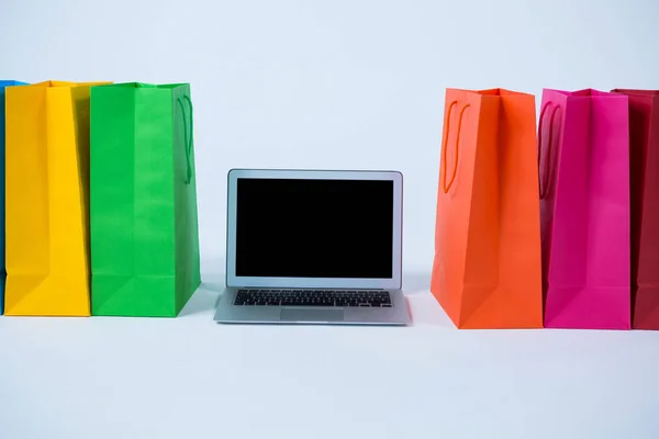 Kleurrijke boodschappentassen met laptop — Stockfoto