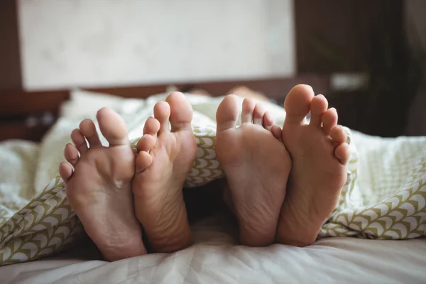 Casal mostrando seus pés enquanto deitado — Fotografia de Stock