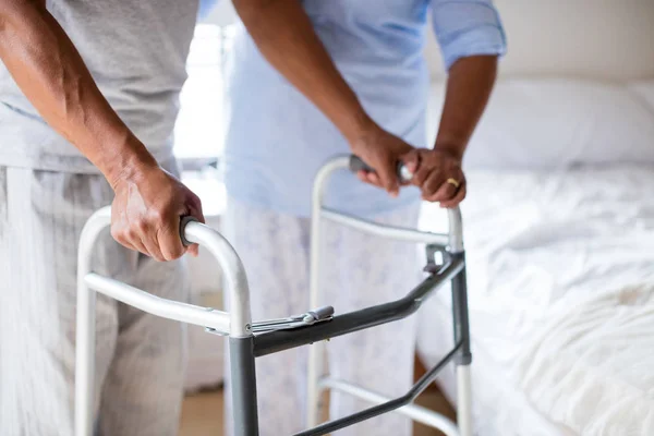 Vrouw helpt man om te wandelen met walker — Stockfoto