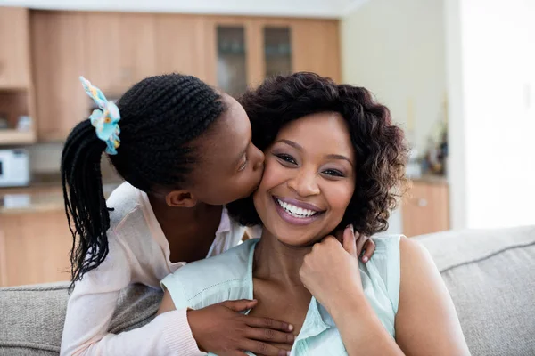 Tochter küsst ihre Mutter im Wohnzimmer — Stockfoto