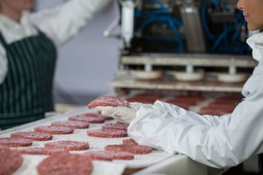 Female butcher processing hamburger patty clipart