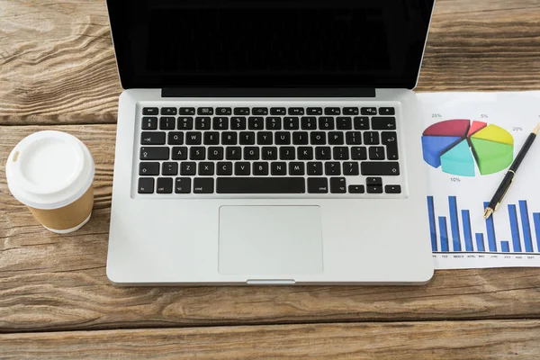 Laptop with disposable coffee cup and business graph — Stock Photo, Image