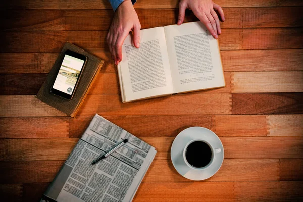 Mão segurando livro em sua mesa — Fotografia de Stock