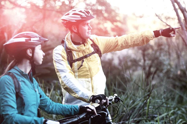Biker paar met mountainbike wijzen op afstand — Stockfoto