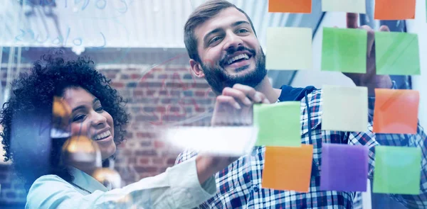 Team looking at sticky notes on window — Stock Photo, Image