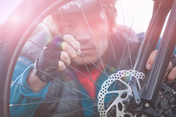 Masculino mountain biker examinando roda dianteira — Fotografia de Stock