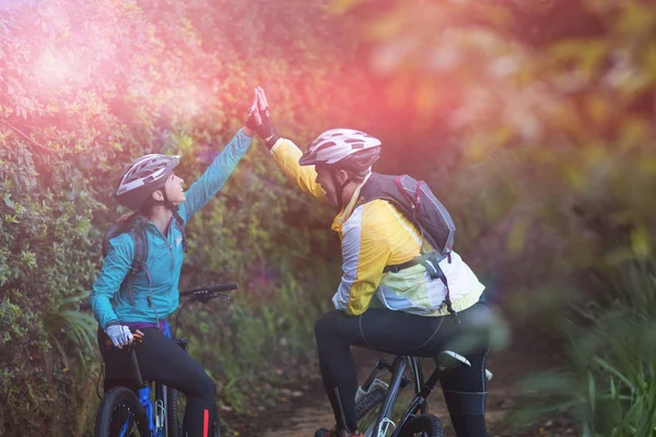 Biker couple giving high five while riding bicycle