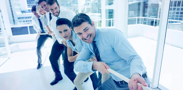 Business people pulling rope in office — Stock Photo, Image