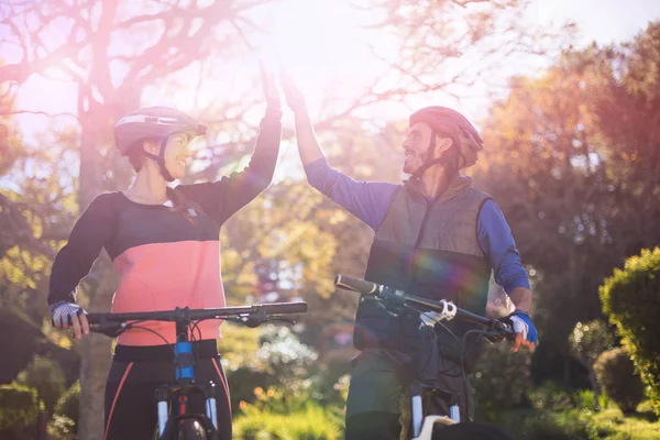 Pareja motociclista dando cinco altos mientras monta bicicleta — Foto de Stock