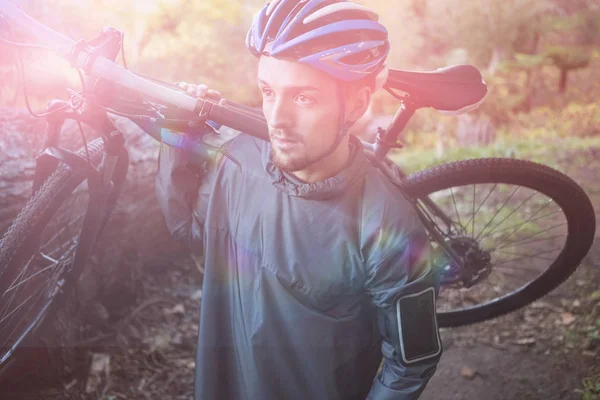 Muž na horském kole přepravující jízdní kolo v lese — Stock fotografie