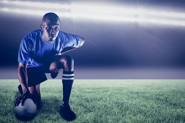 Jogador de rugby ajoelhado enquanto segurando bola — Fotografia de Stock