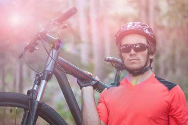 Male mountain biker carrying bicycle in forest — Stock Photo, Image