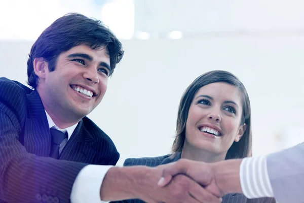 Lächelnder Geschäftsmann und sein Kollege beim Abschluss eines Deals mit einem Partner — Stockfoto