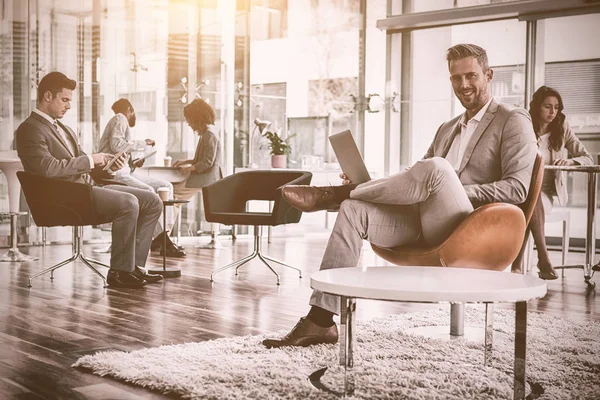 Homme d'affaires souriant utilisant un ordinateur portable au bureau — Photo