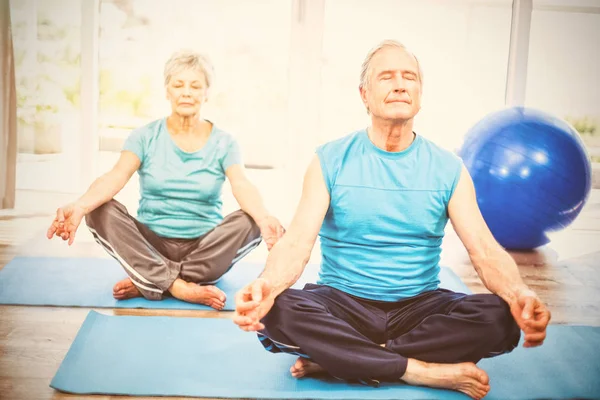 Casal sênior meditando com os olhos fechados — Fotografia de Stock