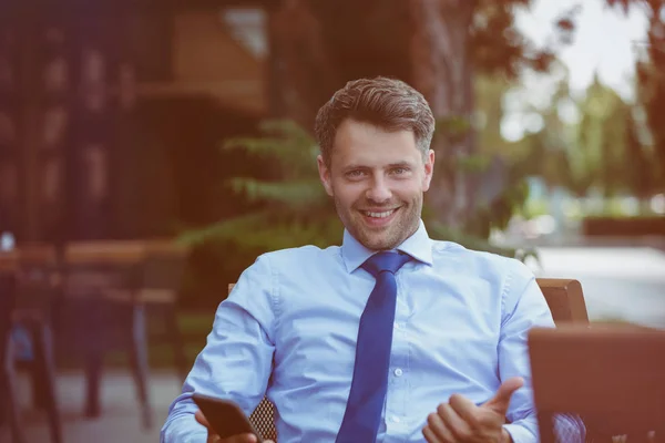 Empresário alegre sentado na cadeira no café da calçada — Fotografia de Stock