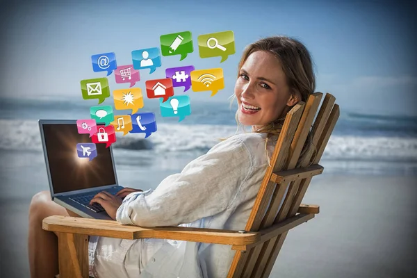 Gorgeous blonde sitting on deck chair using laptop on beach 3d — Stock Photo, Image