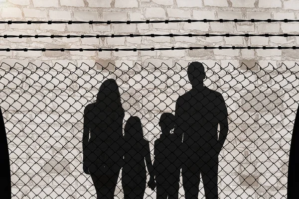 Silhouette de famille joyeuse tenant la main sur une clôture à maillons de chaîne — Photo