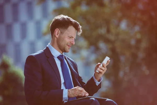 Hombre de negocios sonriente usando teléfono móvil y tableta digital — Foto de Stock