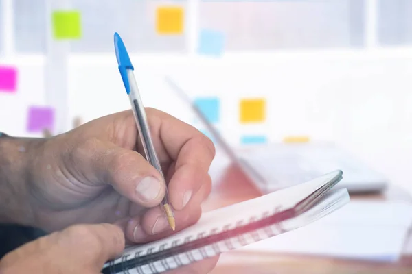 Man writing in spiral book — Stock Photo, Image