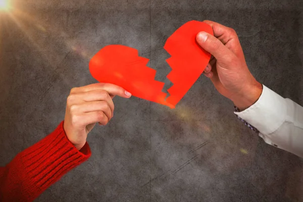 Pareja sosteniendo agrietado corazón rojo forma — Foto de Stock