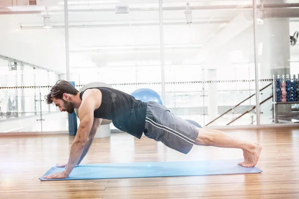 Visão lateral do homem muscular fazendo empurrar para cima no tapete — Fotografia de Stock