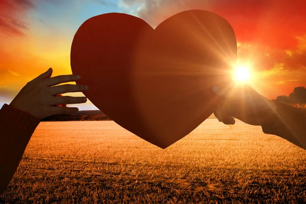 Hands holding orange heart shape paper — Stock Photo, Image