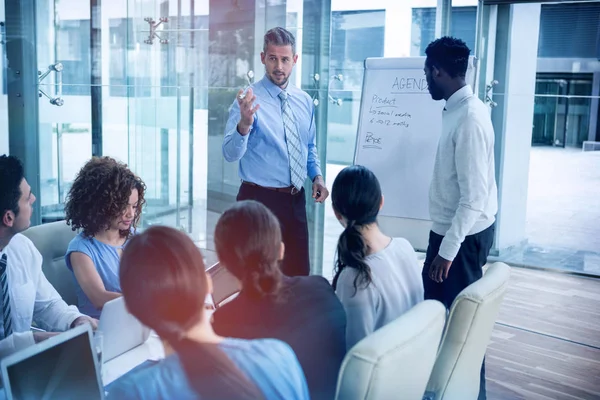 Empresário discutindo no quadro branco com colegas de trabalho — Fotografia de Stock