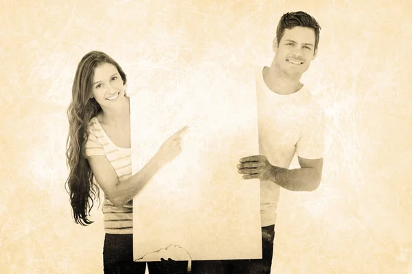 Happy couple pointing a white poster — Stock Photo, Image