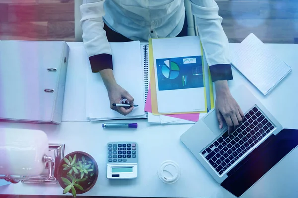 Donna d'affari che utilizza il computer portatile durante la scrittura su blocco note — Foto Stock