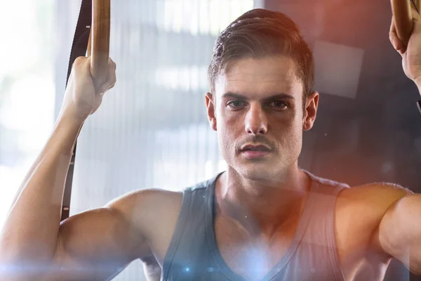 Portrait of young man using gymnastic rings in gym — Stock Photo, Image