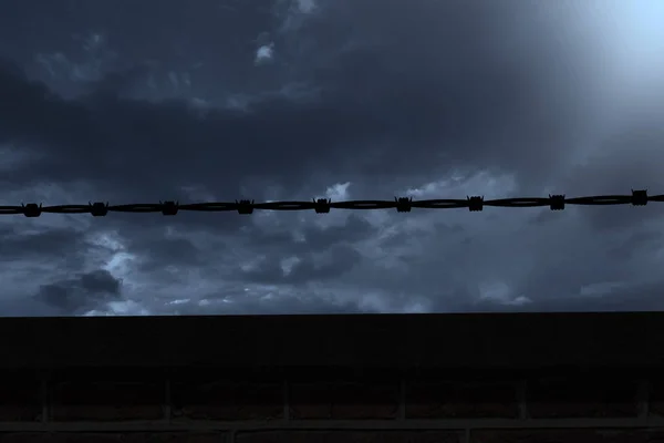Drát ostnatý plot proti zatažené obloze — Stock fotografie