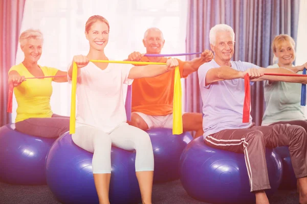 Portrait of seniors using exercise ball and stretching bands — Stock Photo, Image