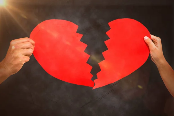 Par händer som håller röda knäckt hjärta form — Stockfoto