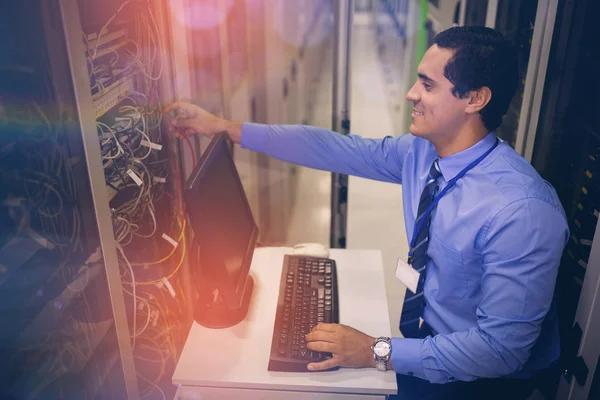 Técnico que trabaja en el ordenador personal mientras analiza el servidor — Foto de Stock