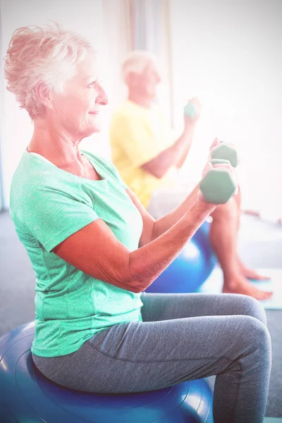 Idosos usando bola de exercício e pesos — Fotografia de Stock