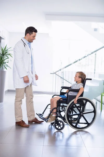 Doutor interagindo com menino incapacitado no corredor — Fotografia de Stock