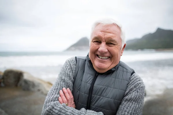 Porträt eines älteren Mannes, der mit verschränkten Armen am Strand steht — Stockfoto