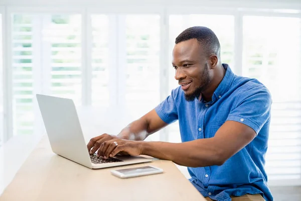 Man zit aan Bureau en met behulp van de laptop in de woonkamer — Stockfoto