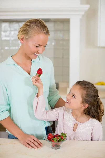 Dochter aardbei geven moeder in de keuken — Stockfoto