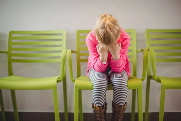 Upprörd tjej sitter på stol i korridor — Stockfoto