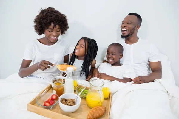 Sonrientes padres e hijos desayunando en el dormitorio —  Fotos de Stock