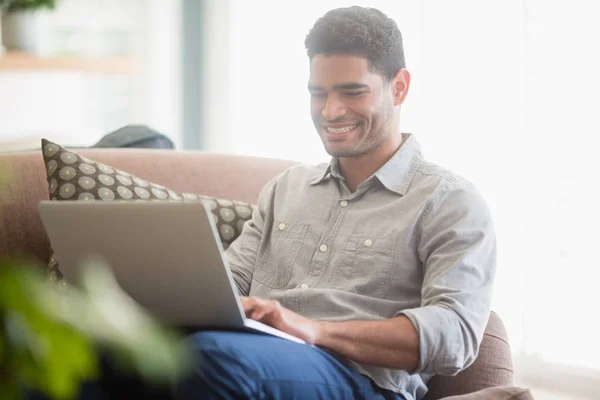 Uomo seduto sul divano e utilizzando il computer portatile in soggiorno — Foto Stock