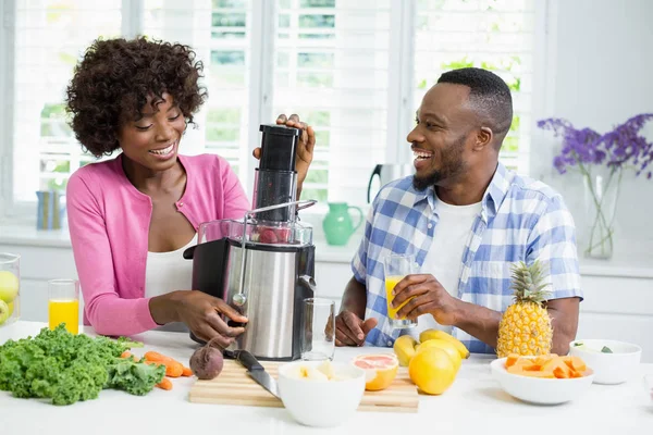 Smiling couple preparing strawberry smoothie in kitchen — Stock Photo, Image