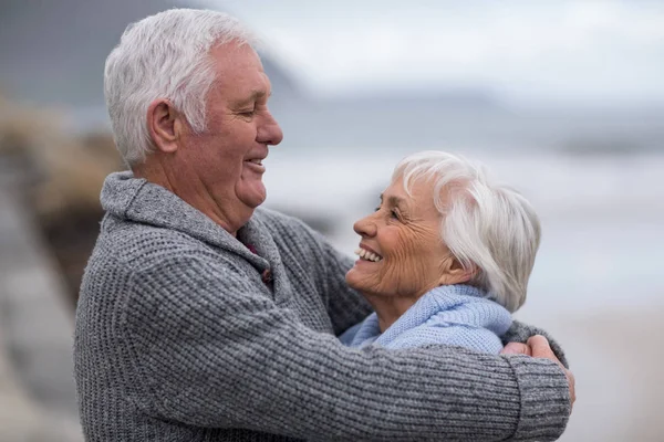 Senior paar omhelzen elkaar op het strand — Stockfoto