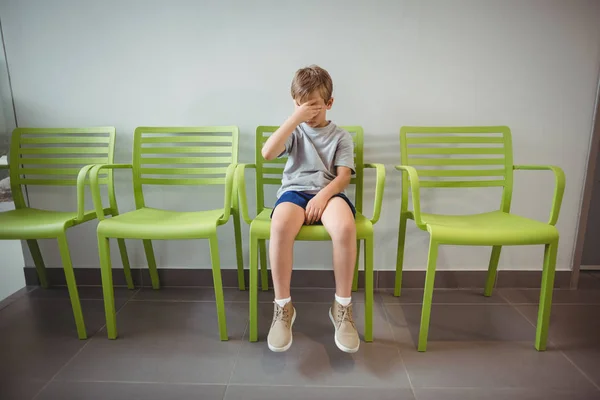 Boos jongen zit op stoel in de gang — Stockfoto