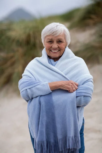 S úsměvem starší ženu zabalenou do šátku na pláži — Stock fotografie