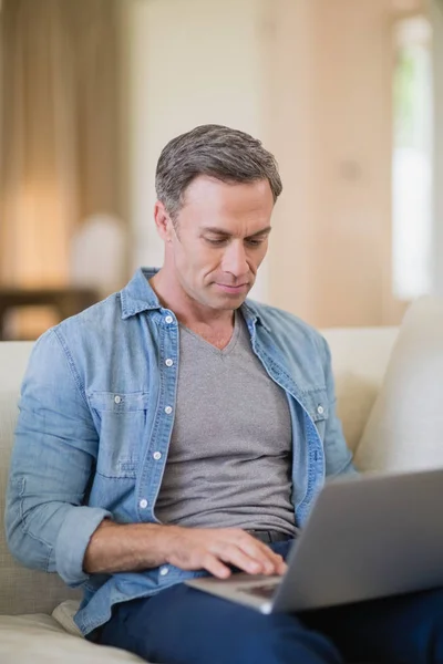 Uomo utilizzando il computer portatile in soggiorno — Foto Stock